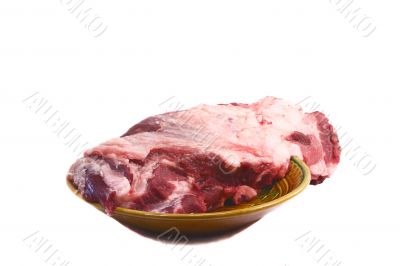 A large piece of raw pork meat on ceramic dish on a white backgr