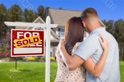 Sold For Sale Sign with Military Couple Looking at House