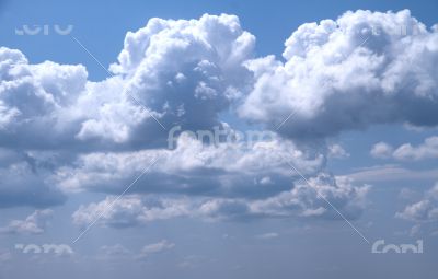 A horizontal shot of bright blue sky with puffy white clouds.