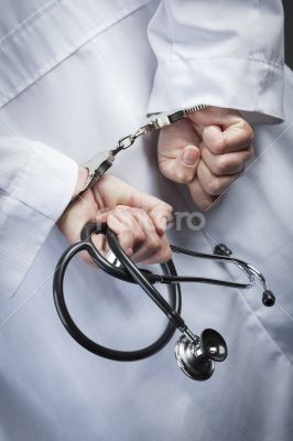 Female Doctor or Nurse In Handcuffs Holding Stethoscope