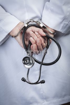 Female Doctor or Nurse In Handcuffs Holding Stethoscope