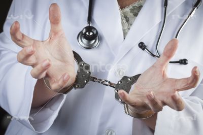 Doctor or Nurse In Handcuffs Wearing Lab Coat and Stethoscope Doctor or Nurse In Handcuffs Wearing Lab Coat and Stethoscope