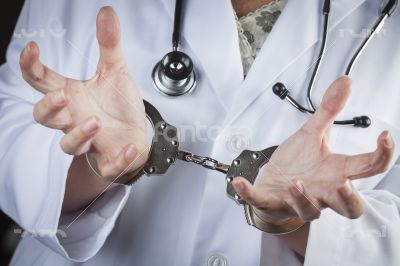 Doctor or Nurse In Handcuffs Wearing Lab Coat and Stethoscope