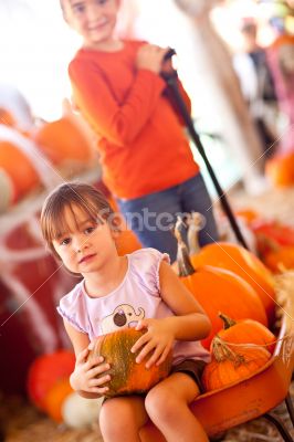 Cute Girl Riding Wagon with Her Pumpkin and Sister