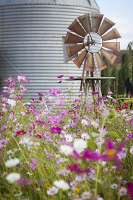 Antique Farm Windmill and Silo in a Flower Field 
