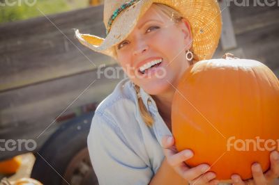 Beautiful Blond Female Rancher Wearing Cowboy Hat Holds a Pumpki