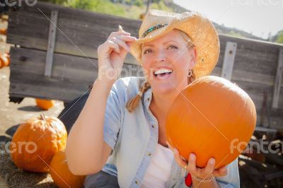 Beautiful Blond Female Rancher Wearing Cowboy Hat Holds a Pumpki