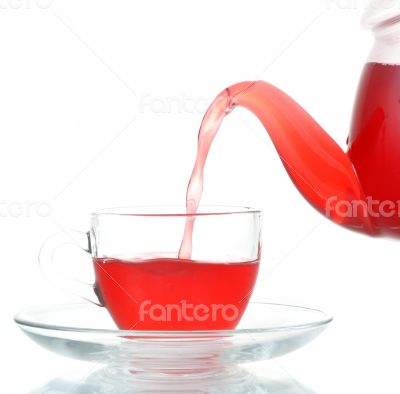 Tea being poured into glass tea cup isolated