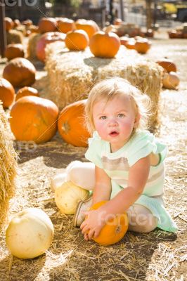 Adorable Baby Girl Holding a Pumpkin at the Pumpkin Patch
