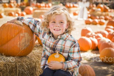 Little Boy Sitting and Holding His Pumpkin at Pumpkin Patch