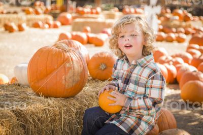 Little Boy Sitting and Holding His Pumpkin at Pumpkin Patch