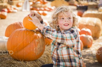 Little Boy Sitting and Holding His Pumpkin at Pumpkin Patch