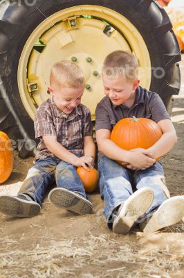 Two Boys Holding Pumpkins Talking and Sitting Against Tractor Ti