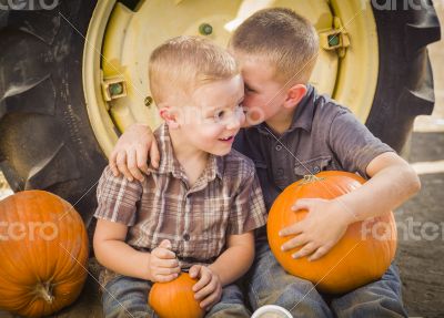 Two Boys Sitting Against Tractor Tire Holding Pumpkins Whisperin