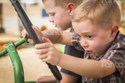 Adorable Young Boys Playing on an Old Tractor Outside