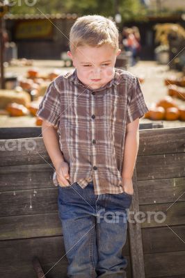 Frustrated Boy at Pumpkin Patch Farm Standing Against Wood Wagon
