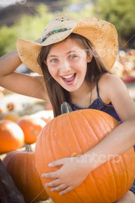 Preteen Girl Holding A Large Pumpkin at the Pumpkin Patch