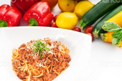 spaghetti with bolognese sauce and fresh vegetables on backgroun