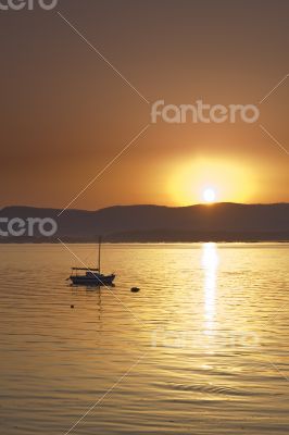 Sunset over the sea with sailing boat