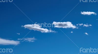 A horizontal shot of bright blue sky with puffy white clouds.