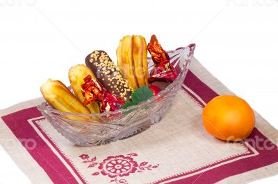 Cakes and sweets in a crystal vase, a tangerine, a napkin on a w