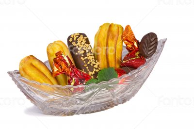 Cakes and sweets in a crystal vase on a white background