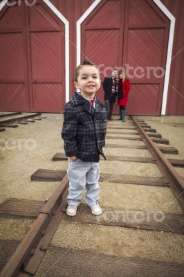 Mixed Race Boy at Train Depot with Parents Smiling Behind