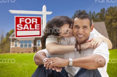 Hispanic Couple, New Home and For Sale Real Estate Sign