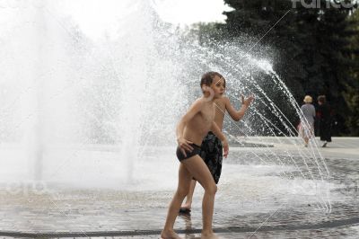 Children walking around splashing fontain in the center of the t