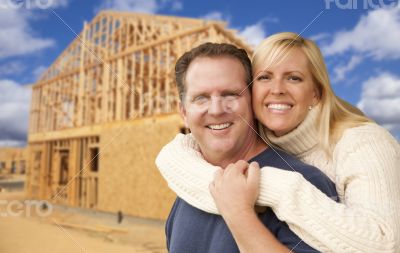 Couple in Front of New Home Construction Framing Site Couple in Front of New Home Construction Framing Site