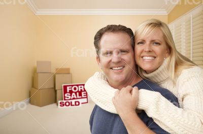 Couple in New House with Boxes and Sold Sale Sign