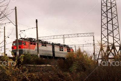 Electic train running by the rails on the fields