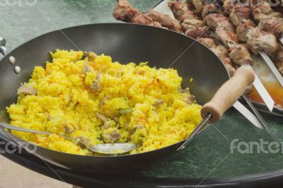 Pilaf in a large frying pan and grilled kebabs.