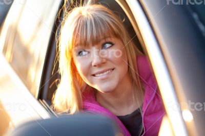 Smiling beautiful girl looks out of a car window