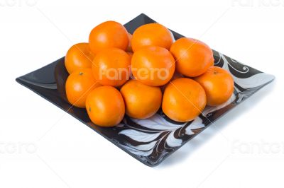 Large ripe tangerines in a glass dish on a white background.