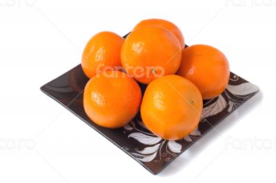 Large ripe tangerines in a glass dish on a white background.