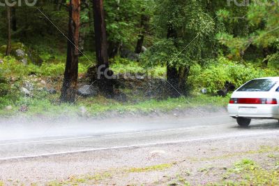 Automobile driving on the puddle on a highway Automobile driving on the puddle on a highway