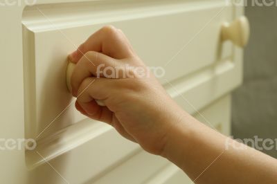 Child`s hand is opening a drawyer 