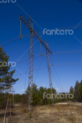 High voltage power lines against the blue sky and the spring for