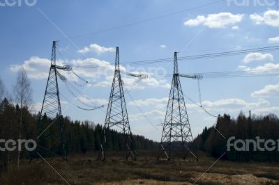 High voltage power lines against the blue sky and the spring for
