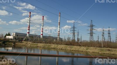 Factory pipes and high voltage power lines against the blue sky 