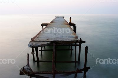 Abandoned concrete wharf in sea within sunrise
