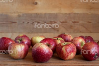 Red apples lie on a wooden surface