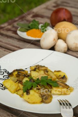 Baked potatoes with mushrooms and parsley on the white plate.