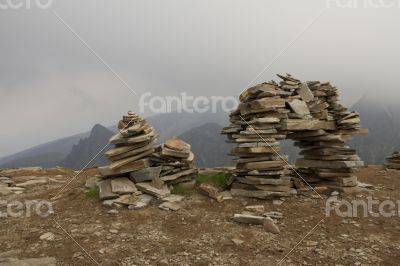 Few flat stones stacked pyramid atop a mountain on the backgroun