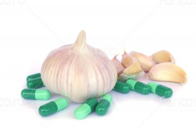 Herbal pills and garlic on a light colored background