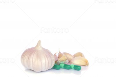 Herbal pills and garlic on a light colored background