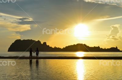 Two children on the beach watching the sunrise