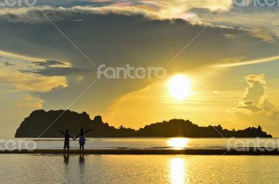 Two children on the beach watching the sunrise