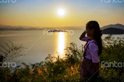 Young woman watching the sunset over the lake